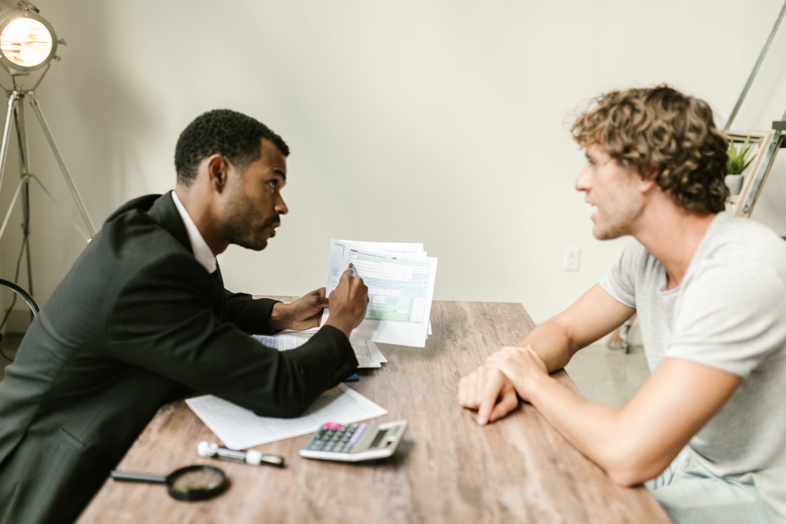 A preparer and a client sitting across a table, going over forms with a calculator