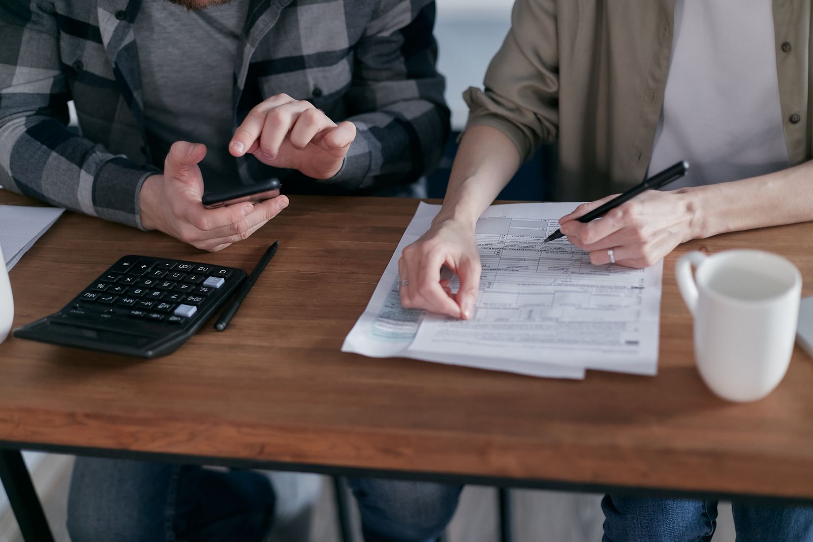 Two people working through a tax form with a calculator